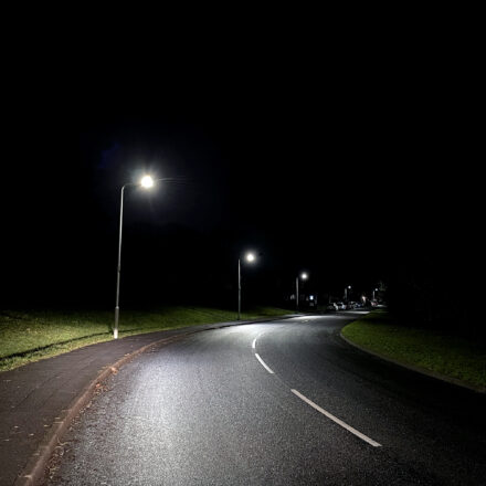 Deserted road at night lit by LED street lights. No people.